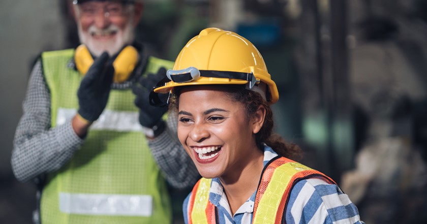 A smiling young woman wearing PPE on a construction site