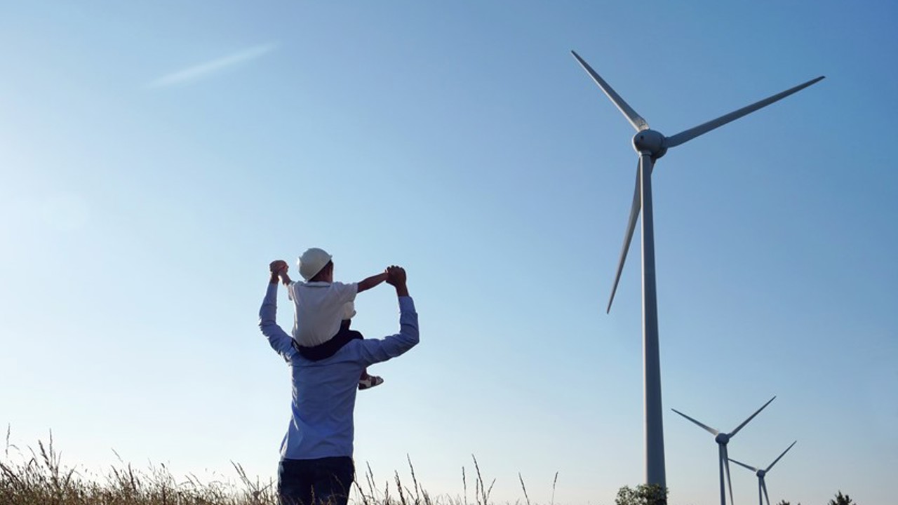 A man and young child by wind turbines