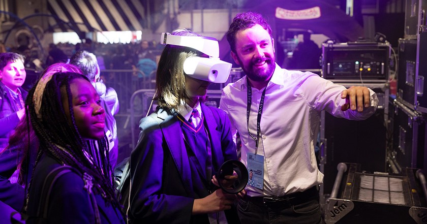 two young people and an adult volunteer using VR on a stand at The Big Bang Fair