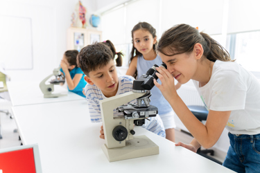 Primary school students using microscope