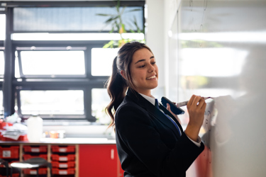 Secondary school student writing on whiteboard