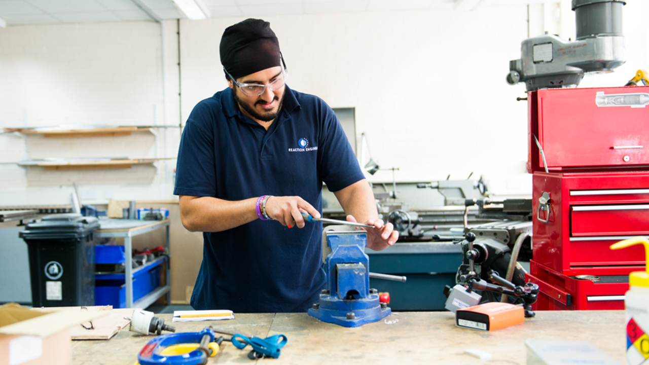 Young engineer in a workshop operating a vice