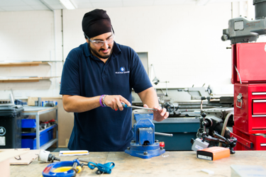 Young engineer in a workshop operating a vice