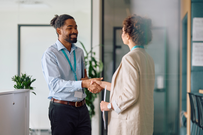 Two people at work shaking hands in an office environment