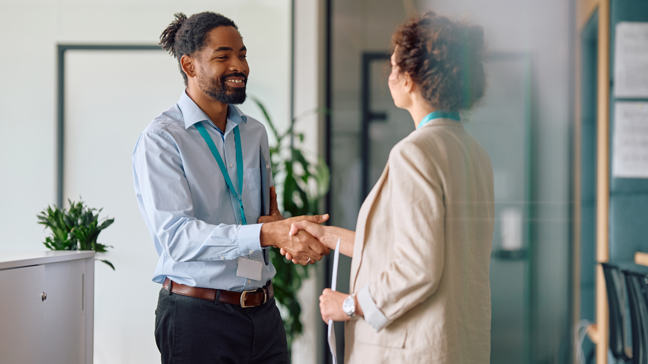 Two people at work shaking hands in an office environment