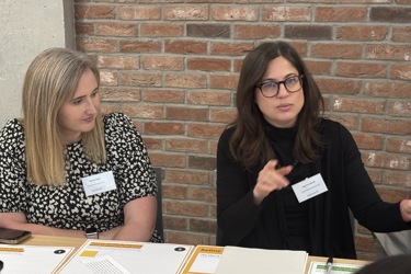 Two people sit at a table talking as they lead working groups 