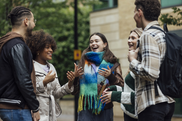 A group of young adults talk animatedly in a group outside