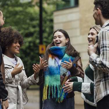 A group of young adults talk animatedly in a group outside