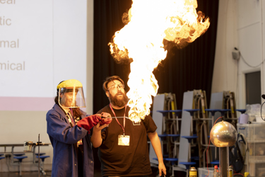 Science demonstration featuring a huge bunsen burner and flame with everyone in safety gloves and goggles