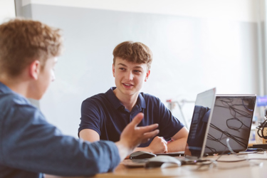 Two people look at screens at a desk