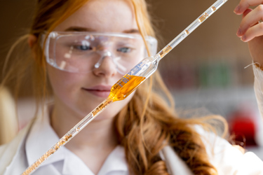 School student working on a science experiment holding up a tube of liquid