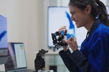 A worker holds equipment and smiles as they look at the screen