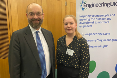 2 people stand facing the camera in front of an EngineeringUK banner