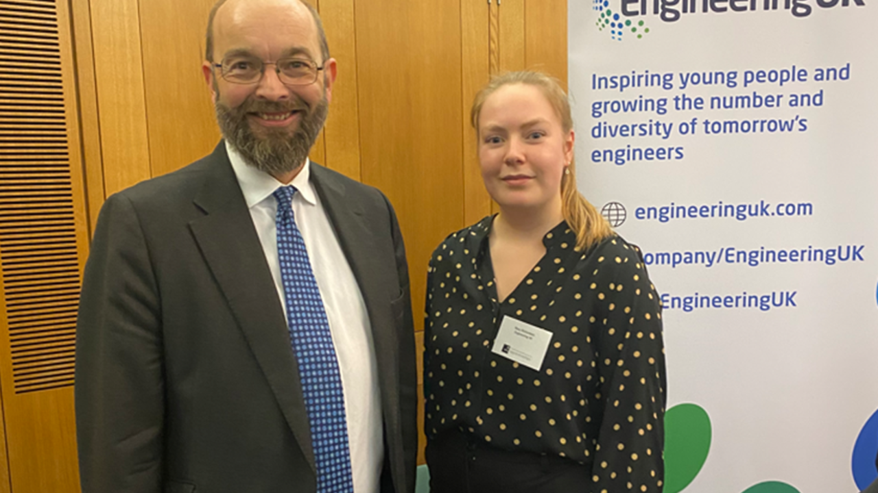 2 people stand facing the camera in front of an EngineeringUK banner