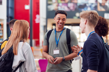 A group of young people smiling and chatting informally in school