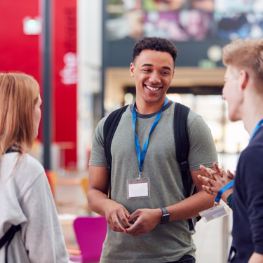 A group of young people smiling and chatting informally in school