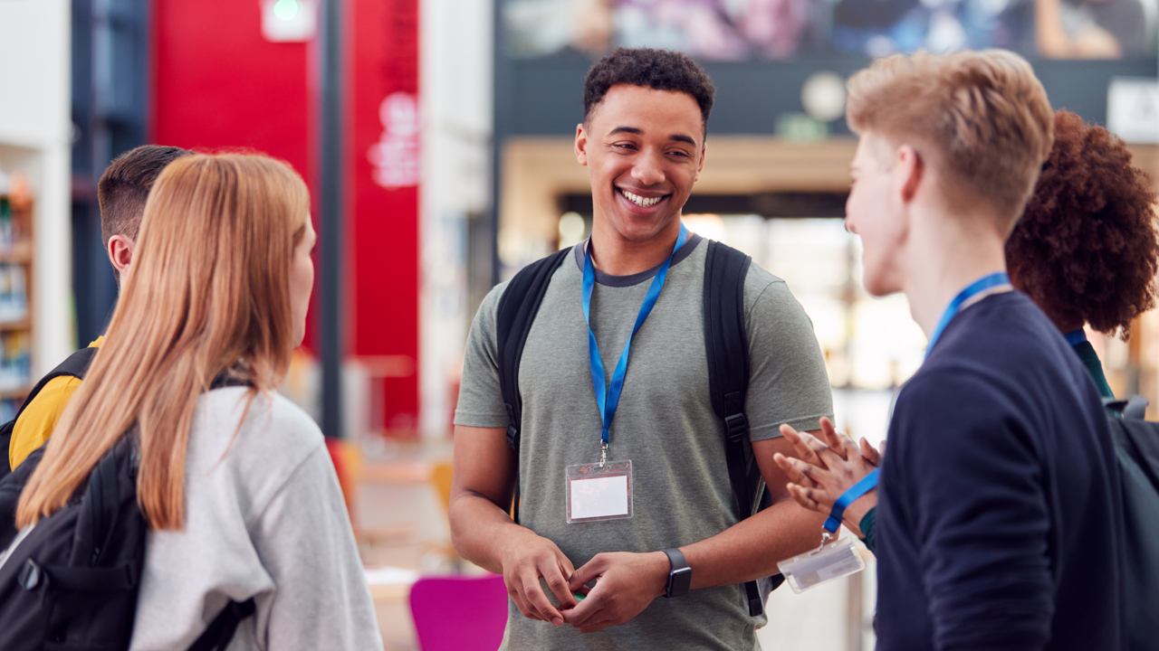 A group of young people smiling and chatting informally in school