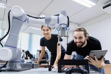 Two workers surrounded by equipment smiling as they work