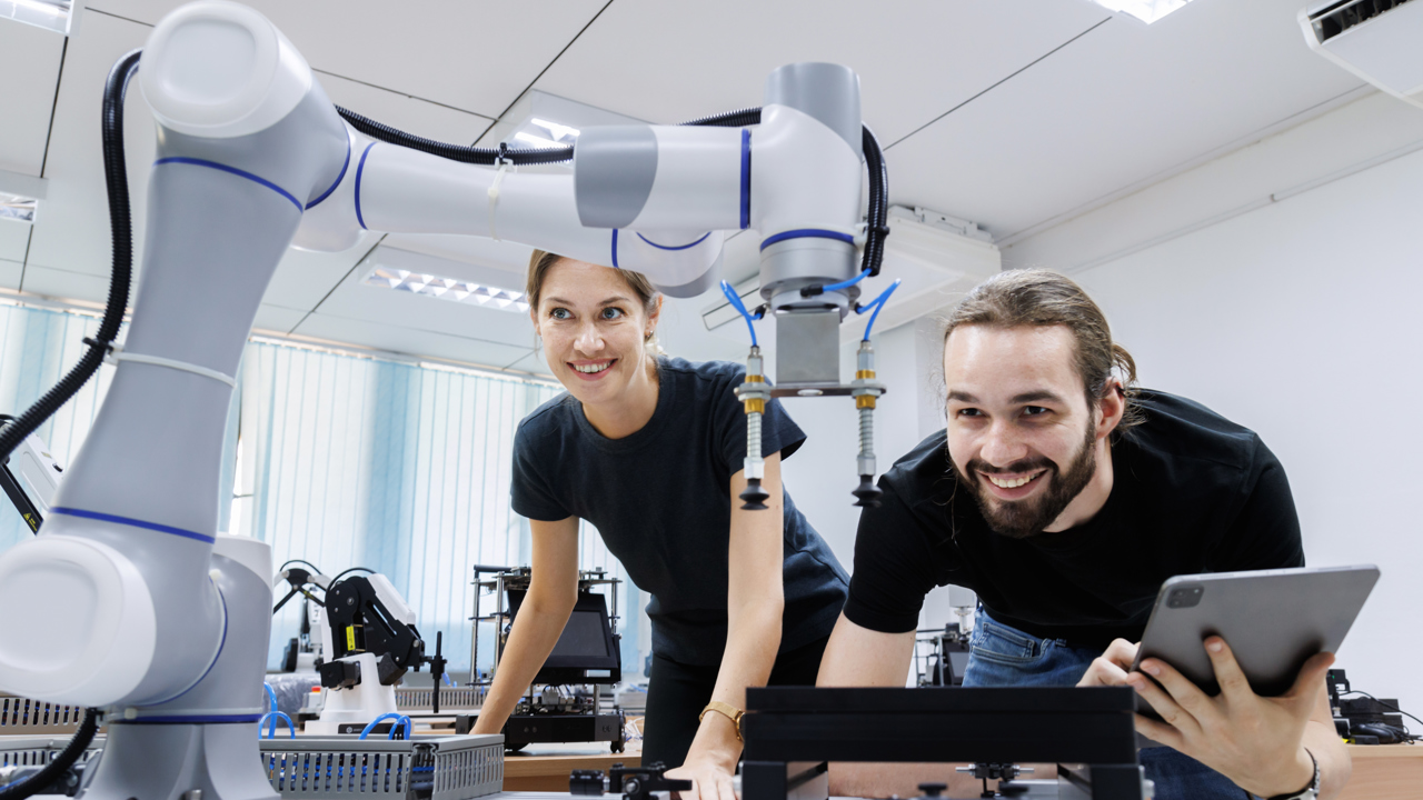 Two workers surrounded by equipment smiling as they work