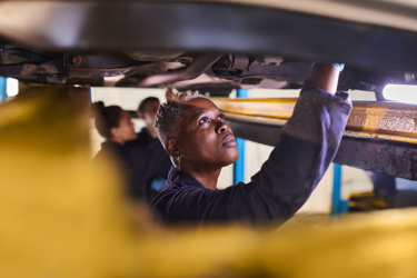 Three engineers pictured working under a vehicle