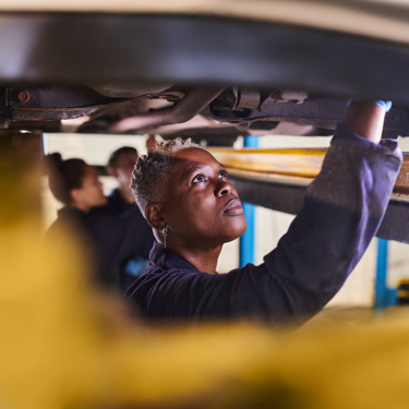 Three engineers pictured working under a vehicle