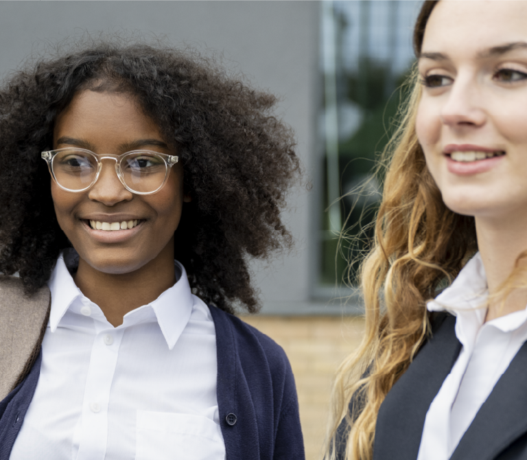 Three young people in school uniform smiling outside