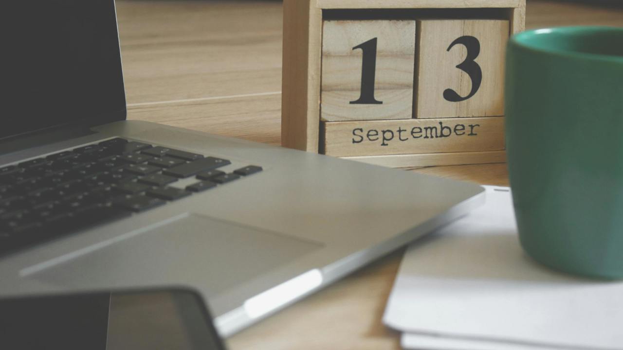 Laptop, phone, papers, mug and calendar on a desk