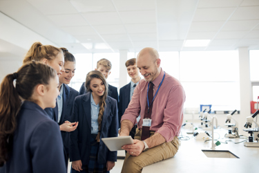 A teacher shows a group of secondary school students a screen in the school science lab