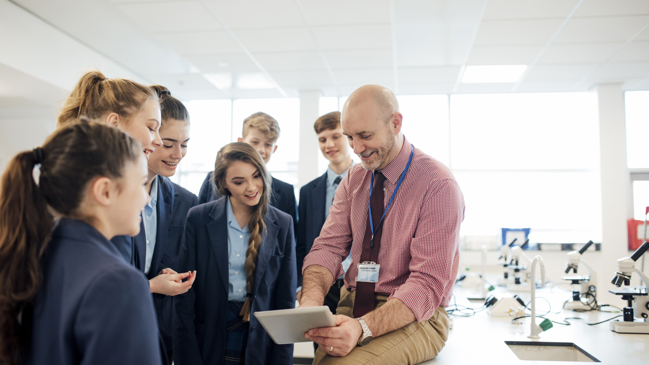 A teacher shows a group of secondary school students a screen in the school science lab