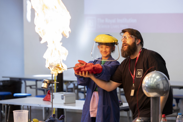 Science demonstration featuring a huge bunsen burner and flame with everyone in safety gloves and goggles