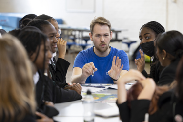 Young people in school working on an experiment with their teacher assisting 