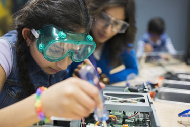 School pupil working with a circuit board with an adult watching on 