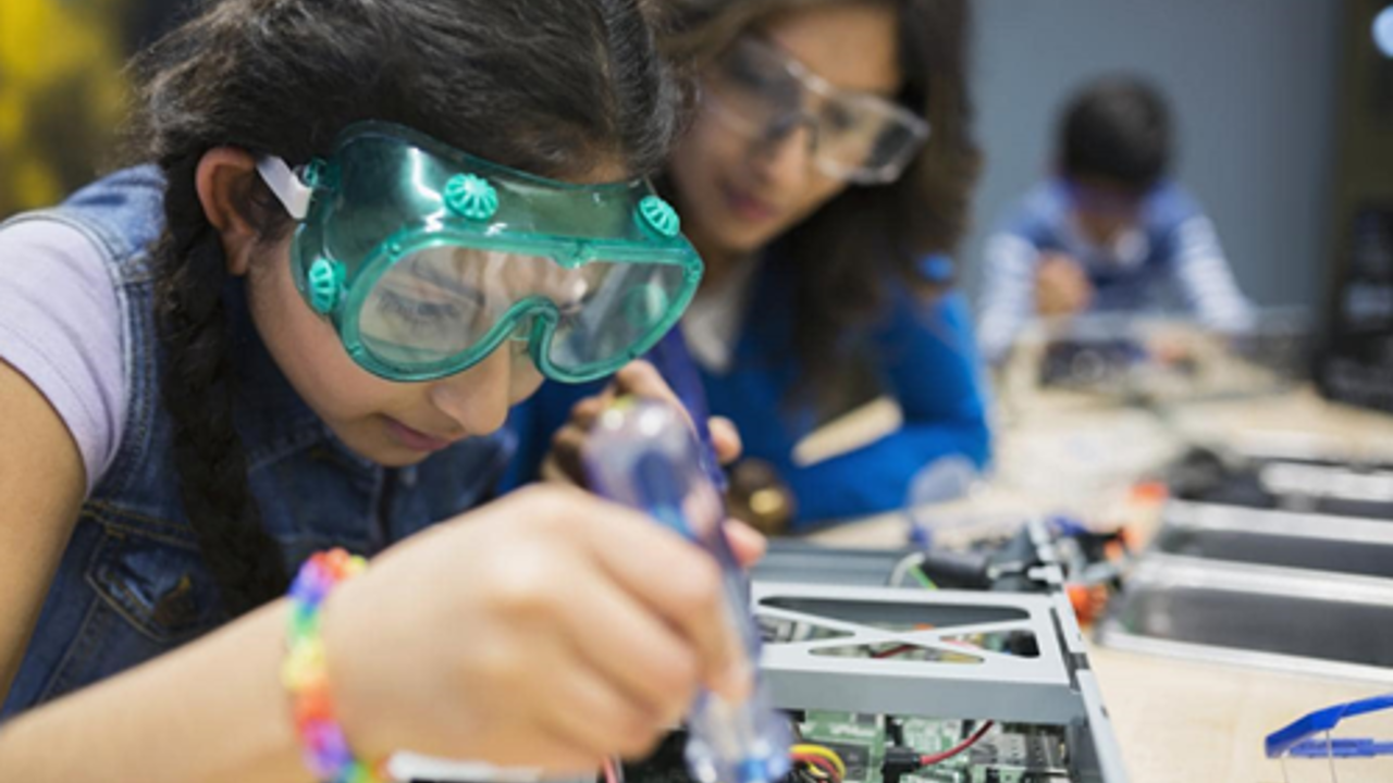 School pupil working with a circuit board with an adult watching on 